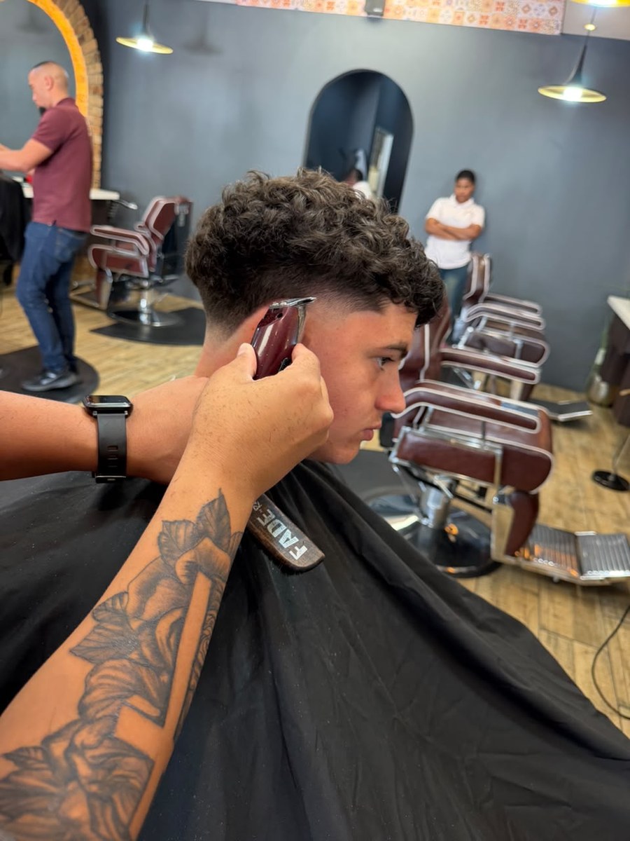 Barber shaping a curly haircut around the temple