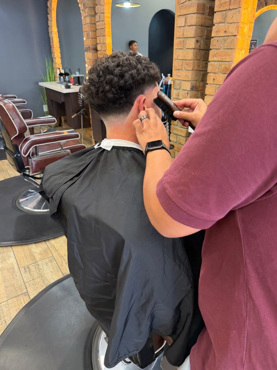 Barber detailing the sides of a curly haircut